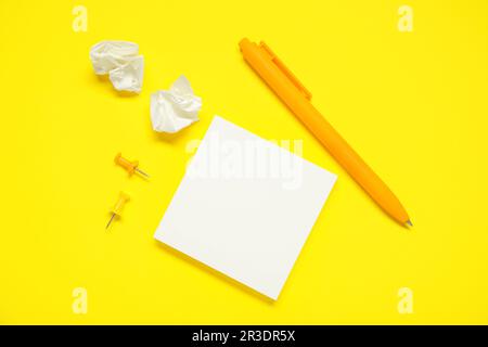 Pen with sticky notes and pins on yellow background Stock Photo