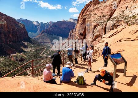 Asian man stretching. Tourists & hikers at top of Canyon Overlook Trail; Zion National Park; Utah; USA Stock Photo