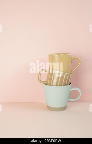 Stack of brown and mint blue mug cups on pink table. pink wall background. copy space Stock Photo