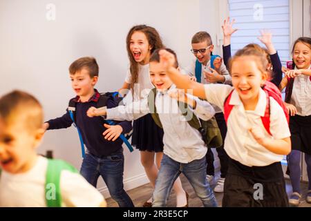 Happy school kids running in elementary school hallway, front view Stock Photo