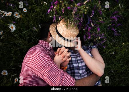 Romantic couple embracing in summer field with blooming wildflowers Stock Photo