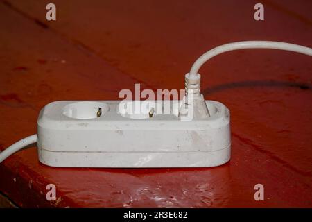 Old dirty extension cord on red floor Stock Photo