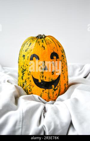 Pumpkin with painted face on a colored background for Halloween. Spider web. Holiday decorations. Stock Photo