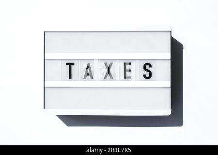 Lightbox board on a white background with the words TAXES in black letters. Stock Photo