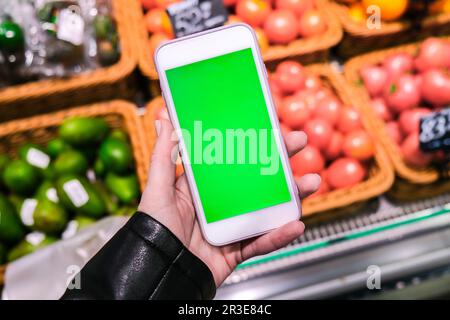 Chroma key. Close up of woman holds smart phone with green screen at grocery store. Shopping center. Department store. Mall. Sho Stock Photo