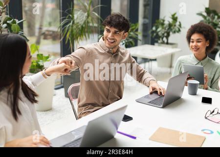 Happy Multiracial Colleagues Bumping Fists Celebrating Achievement In Modern Office Stock Photo