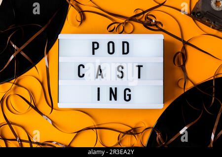 Podcasting lettering and vinyl record album audio cassette tape on yellow background. Millenial. Blogger, podcaster. Retro style Stock Photo