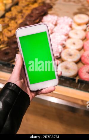 Chroma key. Close up of woman holds smart phone with green screen at grocery store. Shopping center. Department store. Mall. Sho Stock Photo