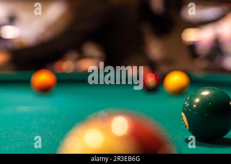 Pool (cue sports, billiards) concept image. Balls on a billiard table in a pool hall. Stock Photo