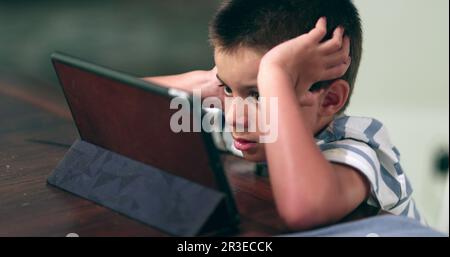 Young boy absorbed watching tablet content online. Kid watches film Stock Photo