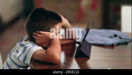 Young boy watching content online on tablet. Child hypnotized by screen device at home Stock Photo