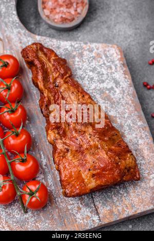 Delicious grilled or smoked pork ribs with salt, spices and herbs on textured concrete background Stock Photo