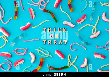 Halloween concept. Halloween party decorations with words TRICK OR TREAT, sweets, top view flat lay on blue background Stock Photo