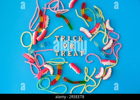 Halloween concept. Halloween party decorations with words TRICK OR TREAT, sweets, top view flat lay on blue background Stock Photo