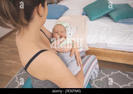 Mother holding and rocking baby sitting on fitball Stock Photo