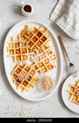Belgian or Brussels waffles with maple syrup and puffed quinoa pops. Homemade waffles in a white ova Stock Photo