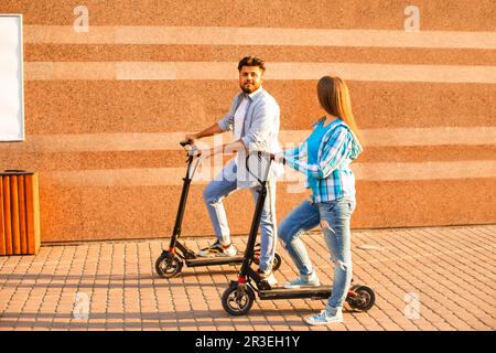 The young couple spend time together riding electric scooter in the city Stock Photo