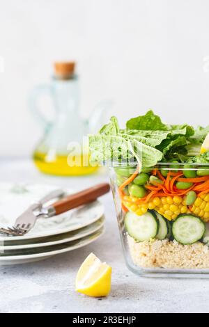 Healthy salad with couscous, carrots, cucumber, green beans, soybeans, corn and an egg on a gray con Stock Photo