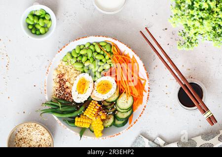 Healthy salad with couscous, carrots, cucumber, green beans, soybeans, corn and an egg on a gray con Stock Photo