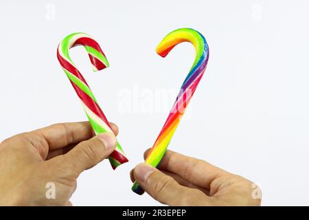 Multicolored lollipops. Hands holding two sweet candies in the shape of heart. Love and Saint Valentine's concept. Lollypops on white background. Swee Stock Photo