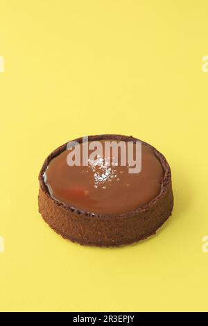 Chocolate tartlet with salted caramel on yellow background Stock Photo