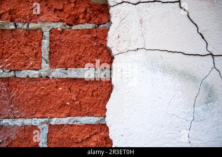 Old red brick wall with peeled off plaster close-up Stock Photo