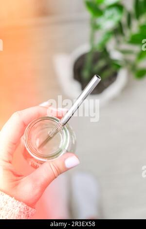 Top view female hand drinking water from eco bottle with metal reusable straw tube. The concept of healthy nutrition, environmen Stock Photo