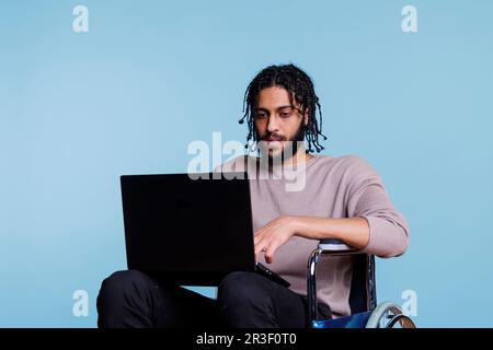 Arab man with physical impairment coding on laptop Stock Photo