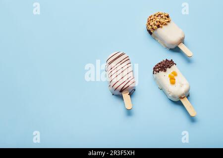 Mousse dessert with fruit flavors in the form of popsicle ice cream on blue background. Stock Photo
