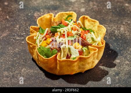 Taco salad in tortilla bowl with beef, cheese, corn and lettuce Stock Photo