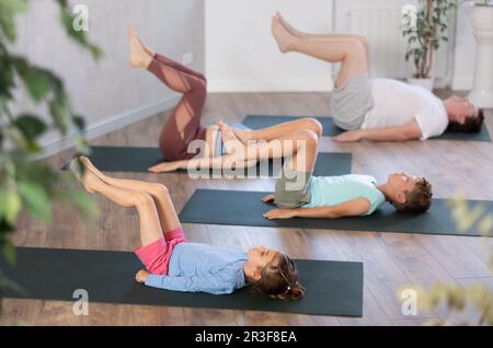 Mom, Dad, Daughter and Son practices yoga do Bridge pose, Sarvangasana Stock Photo