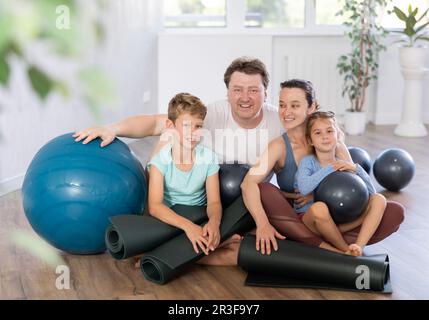 Portrait of happy family engaged in pilates sitting on the floor Stock Photo