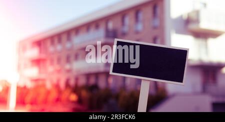 Blank Black billboard against new apartment building Empty mockup template Blackboard label Home for rent. Apartments for sale. Stock Photo