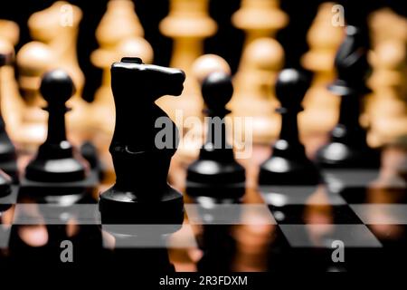 Close up of Chess pieces on a reflective mirror board surface with black background Stock Photo