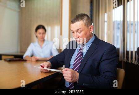 Shocked office employe reading papers with dissatisfied female manager Stock Photo