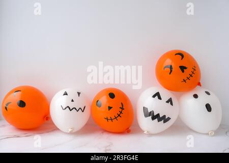 Painted Jacks face on balloons. Orange and white balls preparation diy for halloween party. Halloween home activities. Handmade Stock Photo