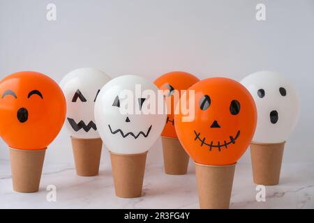 Painted Jacks face on balloons. Orange and white balls preparation diy for halloween party. Halloween home activities. Handmade Stock Photo