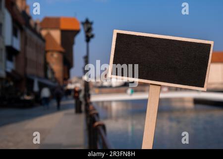 Empty mockup template Blackboard label against Gdansk beautiful old town over Motlawa river. The Zuraw Crane and colorful gothic Stock Photo