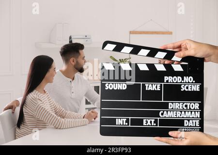 Shooting movie. Second assistant camera holding clapperboard in front of actors at film set Stock Photo