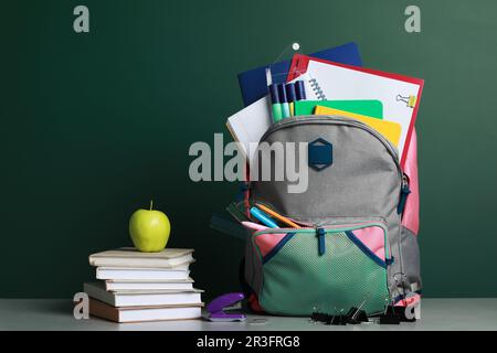 Backpack with different school stationery on white table near chalkboard Stock Photo