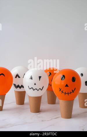 Painted Jacks face on balloons. Orange and white balls preparation diy for halloween party. Halloween home activities. Handmade Stock Photo