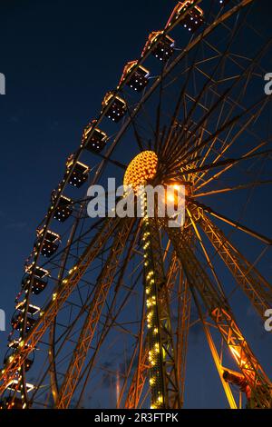 Ferris Wheel Lights at Night. Neon colored lights flashing on the Ferris wheel. Amusement park at night. Entertainment and fun. Stock Photo