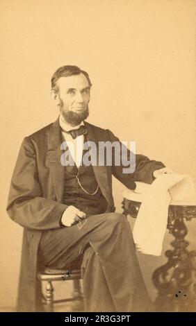 Abraham Lincoln, U.S. President, seated portrait, holding glasses and newspaper, 1863. Stock Photo