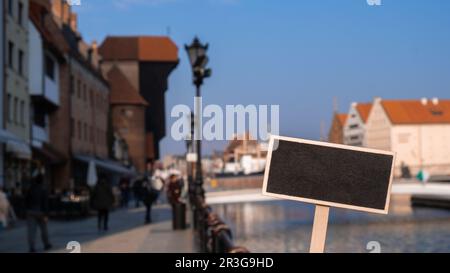 Empty mockup template Blackboard label against Gdansk beautiful old town over Motlawa river. The Zuraw Crane and colorful gothic Stock Photo