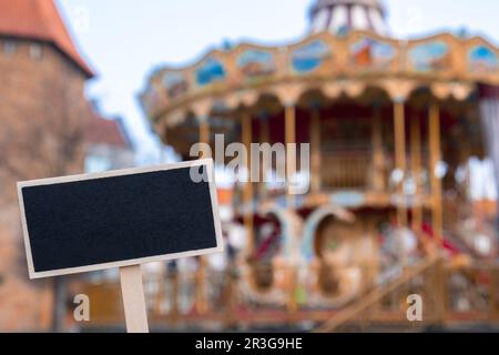 Empty mockup template Blackboard label against Carousel in amusement park. Old-fashioned merry-go-round carousel Stock Photo