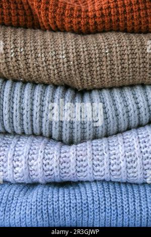 Stack of cozy knitted warm sweater. Sweaters in retro Style. Orange and blue colors. Cozy hygge concept Copy space Stock Photo