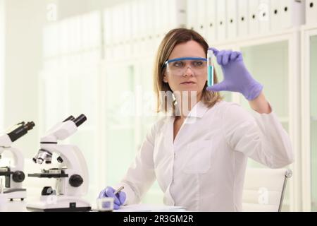 Scientist in goggles examines condition of blue reagent Stock Photo