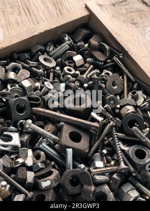 Old rusty bolts and nuts in a wooden box on a workbench Stock Photo