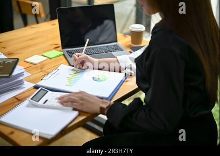 Close-up image of a professional millennial Asian businesswoman or female financial assistant using calculator and analyzing financial reports at her Stock Photo