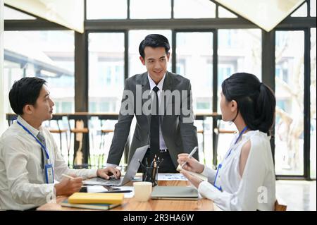 A professional and successful Asian male boss leads the meeting with his team in the meeting room. Businesspeople concept Stock Photo